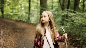 Child with a backpack walking in the forest, a kid walk alone among the trees. Portrait of cute little girl in the forest.