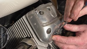 The mechanic installs and screws the valve cover