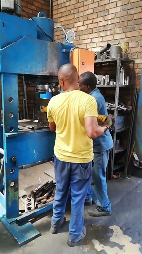 PLACING DAMAGED PISTON ON HYDRAULIC PRESSING MACHINE DURING REPAIR IN MECHANICAL WORKSHOP
