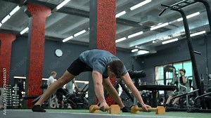 Strong muscular fit man standing on hands holding on push-up stop. Athletic male taking static pose to strengthen cortical muscles during training in gym. Male gymnast doing tagged out handstand.