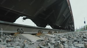 A view from below on the railway and freight train in motion. Close-up of the wheels.