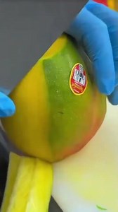cutting a honey mango by peeling off the very thin skin with a sharp knife