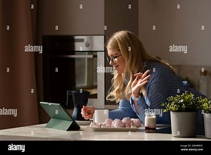 Woman multitasking with tablet and breakfast. Morning routine at remote work. Girl communicates with relatives via video communication Stock Photo - Alamy