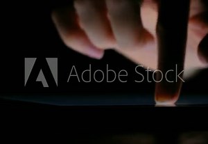 Hand writes on the tablet with your finger in the dark close up, 4k.