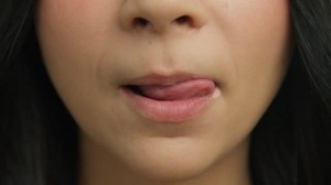 若い女性はセクシーな唇をかむと舌で舐める顔 魅力的な若い女の子の唇と口 健康的な肌の顔のメイク 官能的な女性の閉鎖舐めふっくらした唇でスローモーション笑顔