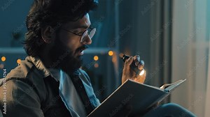 Bearded adult man in glasses at night home living room with flashlight shines on book reads preparing for exams reading bible, faith concept. 30s guy enjoying history in textbook novel at nighttime