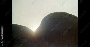 Sheer impregnable fortress wall in sunset sunlight. Medieval defensive castle bastion outside exterior. Down-up epic view of historic landmark. Vintage footage of overscan archival film. 1980s archive