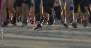 Runners feet during in running marathon. Marathon athletes legs in urban city morning at sunrise, front view, zoom out, slow motion. Record 50 fps render 25 fps.