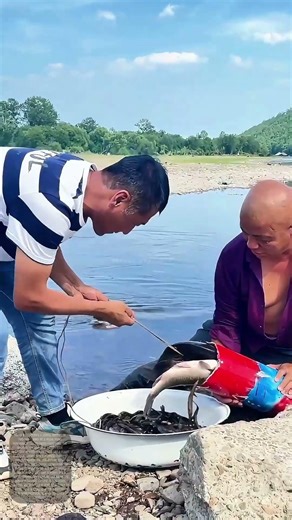 "Catching the Catch: Two Men Enjoying a Successful Fishing Trip with Homemade Tools"