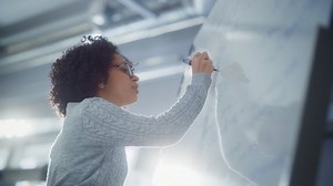 Une scientifique noire résout les problèmes et l'équation des maths en utilisant le tableau blanc. Le génie, la conceptualisation et la percée dans le concept scientifique
