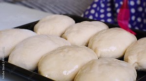Chef's apprentice greases pies with a silicone brush with vegetable oil for beautiful golden crust. Cuisine of peoples. Black baking tray. Close-up side view with cinematic look. Handheld shot