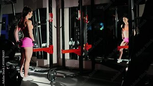 Athletic woman, a professional bodybuilder posing in front of a mirror, shows muscles