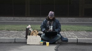 Homeless man with a laptop sitting on the sidewalk - Free Stock Video