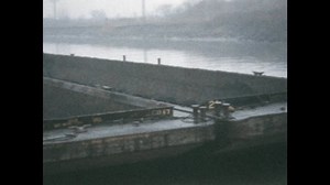 1950s: Coal barges next to a dock, being unloaded by a crane.