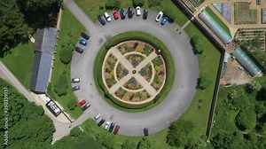 Circular symmetrical landscaped gardens with surrounding car park and green gardens