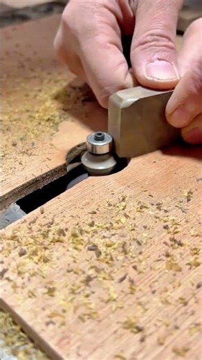 A person is using a router bit to round the edge of a wooden block