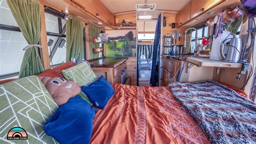 Full Tiny Home Tour! These two went to Europe and quickly realized that following the social American way of life was not in their future. Since then, they’ve been living full-time in a self-converted 2005 Ford E350 Shuttle bus. Eric and Robbyn share many storage hacks and authentic tiny living perspectives. Their home has a cool layout with semi-separate living spaces, an abundance of natural light through the original windows, and unique decor. There’s a beautiful glass door for the entryway a