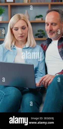 Happy middle aged couple looking at laptop screen sitting on sofa at home. Woman and man in living room searching internet typing online using computer watching video surfing internet. 4k Stock Video Footage - Alamy