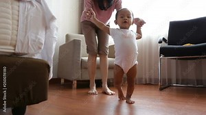 Baby making his first steps with mother assistance