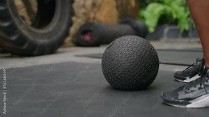 Active woman in fitness gear performs slam ball exercises at outdoor gym, surrounded by rich plants. Intense workout session focuses on strength, endurance, high-intensity functional training. Slowmo
