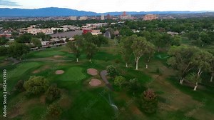 Irrigation of golf course outside of Albuquerque, New Mexico. Dry desert climate in southwest USA requires country clubs water greens of golf courses. Aerial establishing shot.