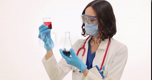 Woman doctor holds conical flask and beaker with color liquids. Female laboratory scientist in safety goggles and mask examines chemical reactions