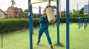 A dedicated young athlete puts in the hard work, vigorously training on gym equipment outdoors to prepare his body. He builds strength and endurance before hitting the field or court for competition