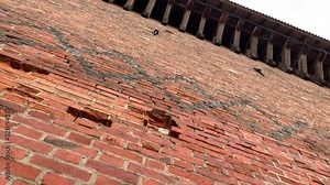 Orange brick wall of a glorious castle. Damaged brick wall. Huge brick castle wall. Weathered texture background, huge stone walls of the castle.