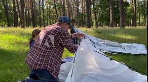 Father skillfully guides children in setting up tent teaching valuable outdoor skills while camping expedition in forest. Kids eagerly assist, excited to be part of camping experience. Family leisure