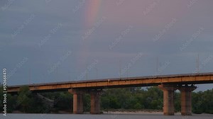 Big rainbow over the old bridge. Road bridge across the river. Rainbow over the river. Rainbow over the bridge. Dramatic sky and rainbow.