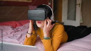 MS Young woman lying on bed and using virtual reality simulator / Milan, Italy