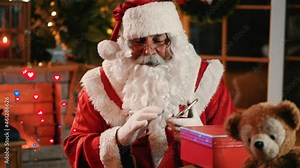 Santa streaming live broadcast video on screen with a lot of emoji like and emotion love. Happy Santa Claus talking to camera sitting at home