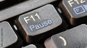 Finger pressing the pause key on a modern laptop computer keyboard, object closeup macro detail, one person.Clicking, pausing an activity, taking a break simple abstract concept, lunch break from work