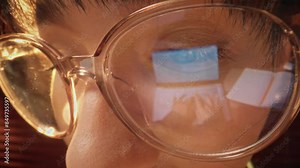 Close-up shot of woman eyes in glasses reflecting a working computer blue screen. Focused on work woman looking at laptop. Macro female eyes. Person watches hypnotizing index finger.