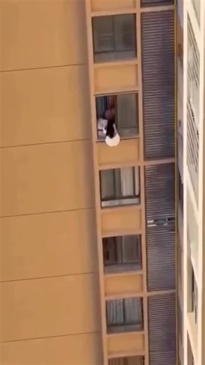 The Buzz Nigeria on Instagram: "A woman in Guangdong, China, was filmed clinging to the outside of a high-rise after her lover allegedly pushed her onto the balcony when his wife returned home unexpectedly. The viral footage shows her dangling from the 10th floor, sliding down pipes and knocking on a neighbour’s window before being pulled to safety. Social media users described the pair as “socially dead” after the public exposure, warning that the dangerous escape could easily have ended in tra