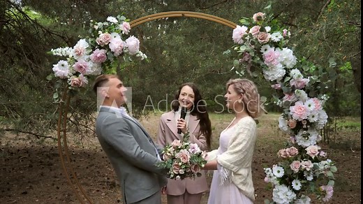 Beautiful and cheerful bride and groom during an outdoor wedding ceremony in the forest.