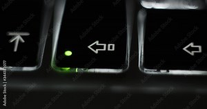 Pressing caps lock on backlit illuminated laptop computer keyboard at night