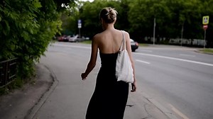 Beautiful young woman walking down the street. Handheld footage.