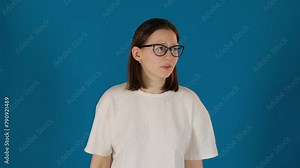 Displeased woman puts glasses on showing puzzlement. Young lady peers through lenses trying to make sense of occurred situation slow motion