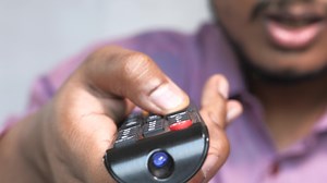 Download A man holding a remote control in his hand for free