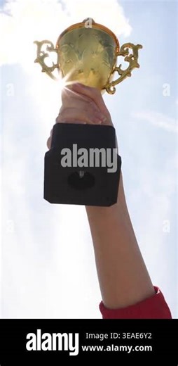 Gold Trophy Lifted High Against Clear Sky, Single Arm Extends Upward Showing Black Base And Ornate Handles Stock Video Footage - Alamy