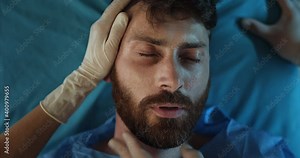 Top view of sick bearded guy heartbeat stopped while he lying on medical stretcher. Ill man in 30s dying while riding in ambulance to hospital. Concept of illness and healthcare