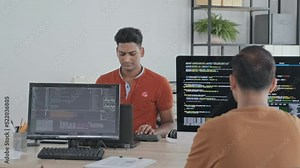 Waist up slowmo of Indian programmers typing program codes on computers in IT office