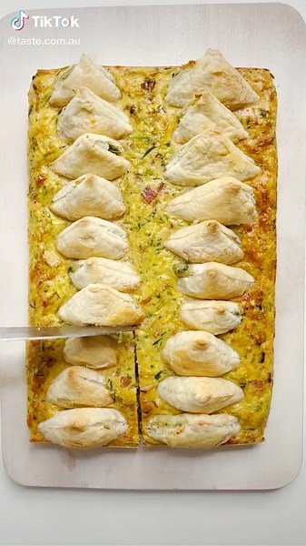 Take your zucchini slice to a new level by topping it with pastry morsels filled with spinach and cheese! Full recipe: https://www.taste.com.au/recipes/spinach-triangle-zucchini-slice-recipe/g84w5yjh | Taste.com.au