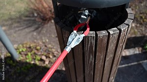 Person with Grabber Reacher Tool putting cigarette butts from ground into trash bin