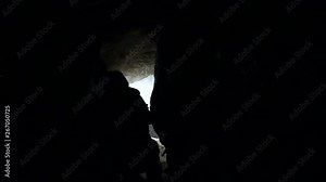 Man explores cave with light in narrow cave. Scientists and miners exploring dark caves. Geologists, explorers, adventurers, pot holing, historians or mining company. It is dangerous in small space.