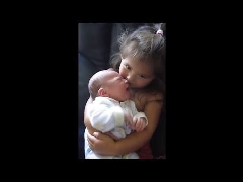 Big sister preciously holds newborn baby brother