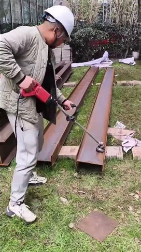 cleaning the long rusty brown metal beam using a red electric grinder tool