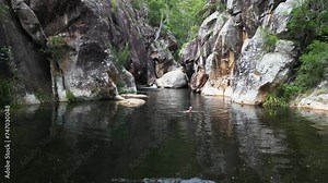 Women tourist swims in a secluded outback Australian billabong. Cinematic drone
