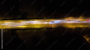 Aerial zoom out view of road intersection with fast moving heavy traffic at night. Time lapse of urban transportation. Rush hour with blurred car trail lights